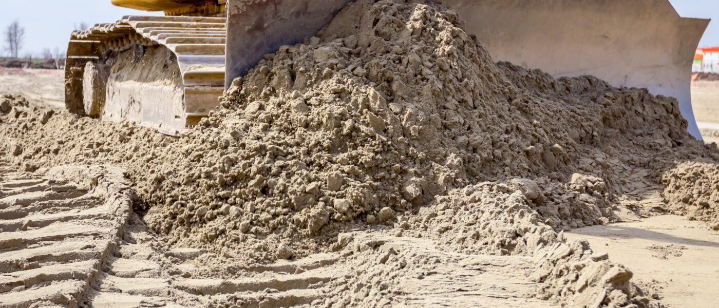 Close up of an earthmoving bulldozer track and blade pushing dirt.